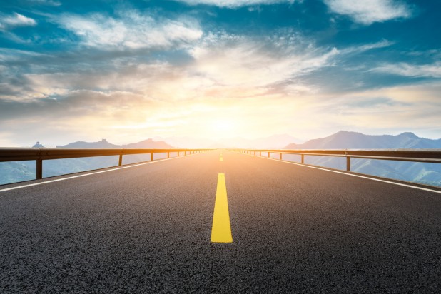 Asphalt road and great wall with mountains at sunset