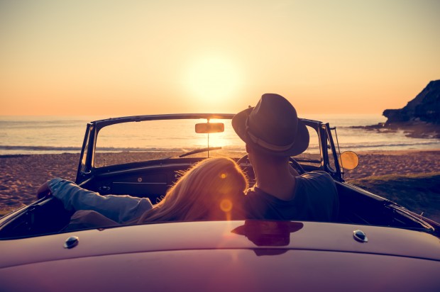 Couple watching the sunset in a convertible car.