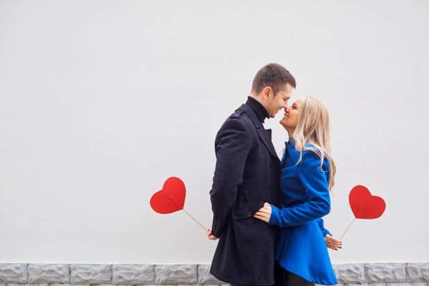 A loving couple in a coat with hearts in hands.