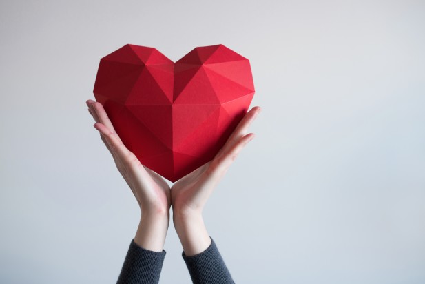 Female hands holding red polygonal heart shape