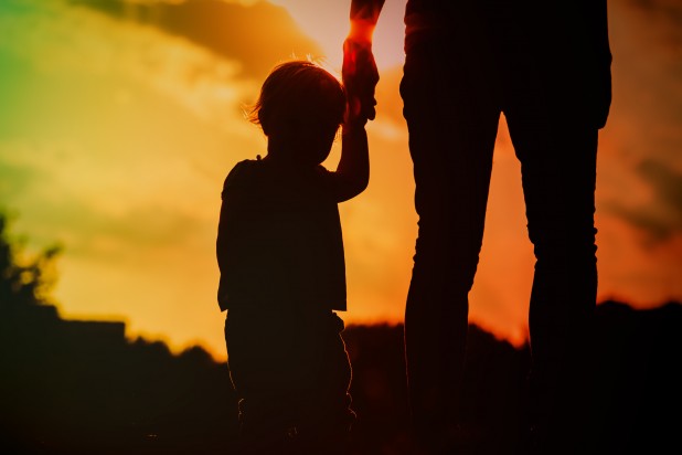 silhouette of mother and daughter holding hands at sunset