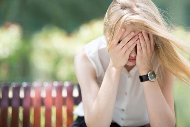 Sad woman sitting on bench outdoors